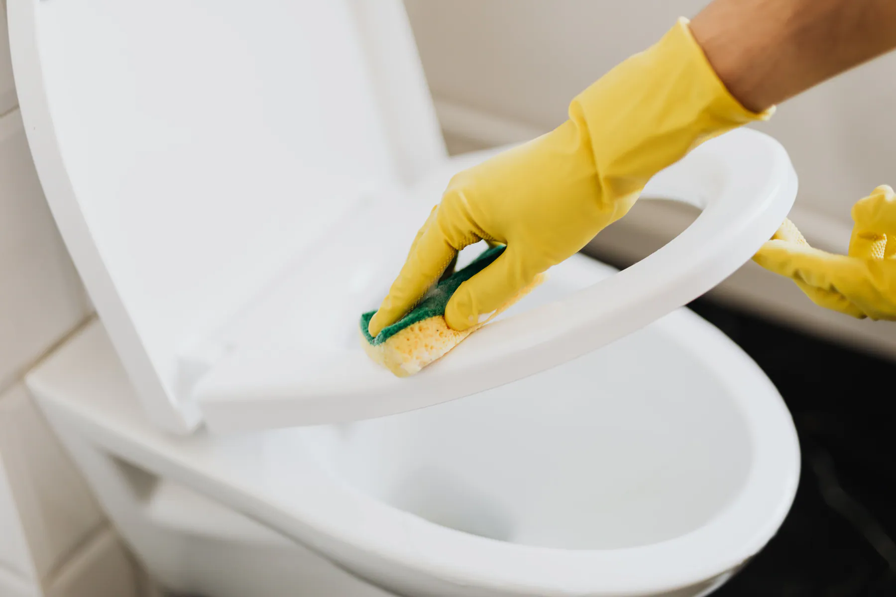 Gloved hand carefully cleaning a bathroom fixture